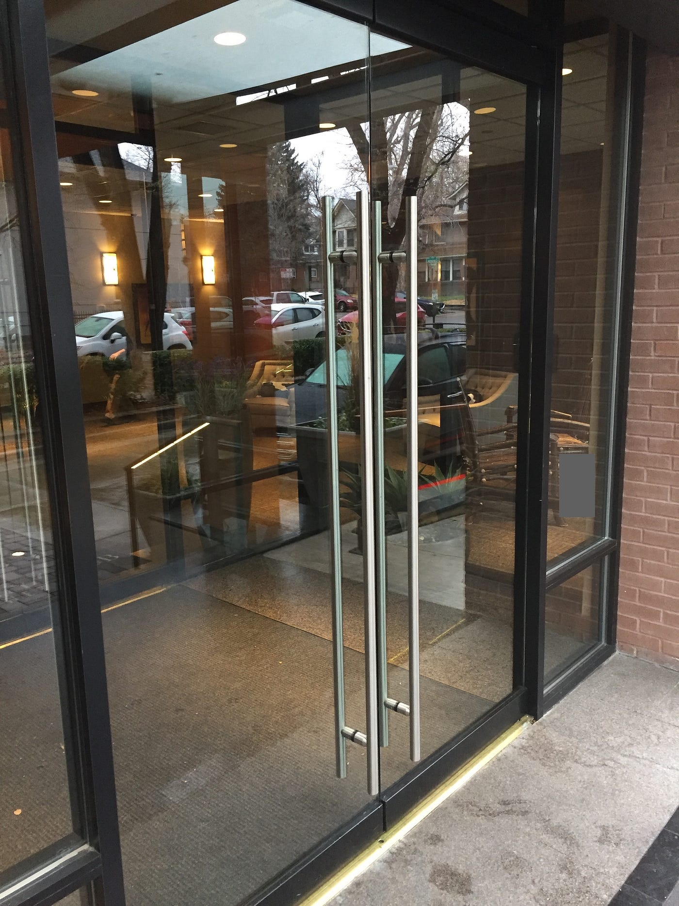 An exterior shot of an office glass door that has long metal handles on both sides.